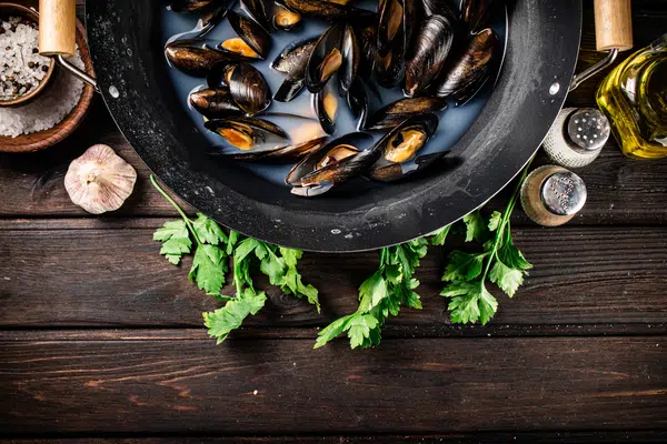 Mussels in a saucepan with parsley and spices.